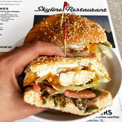 hand holding half a chicken sandwich showing cross section with jalapenos