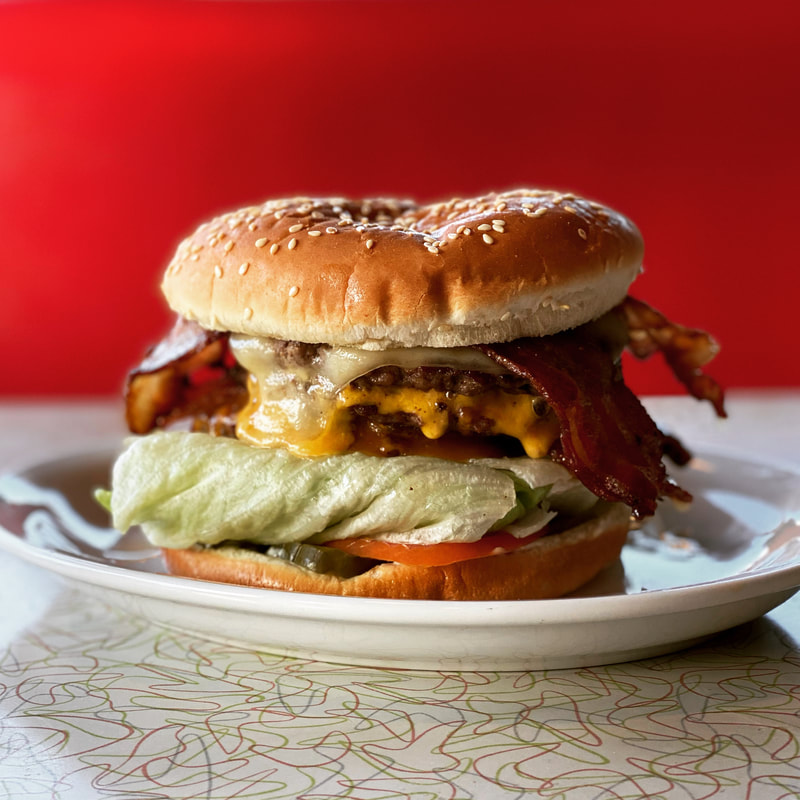 three patty burger with cheese and bacon red background