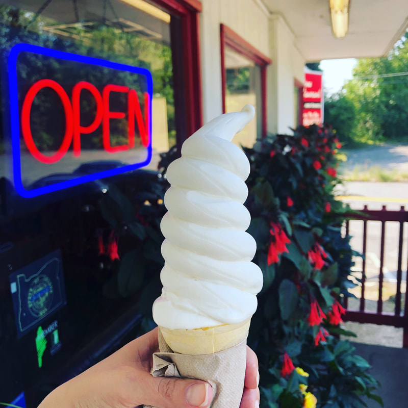 soft-serve ice cream cone in front of neon open sign